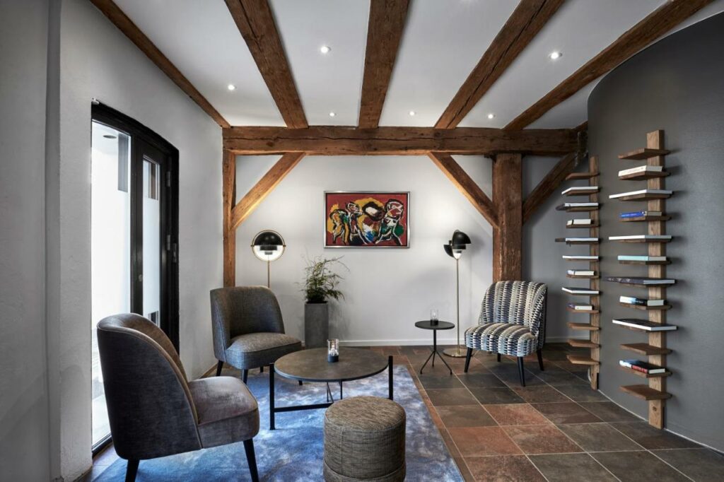 Zona comum do 71 Nyhavn Hotel com mesa, cadeiras e duas estantes com livros.