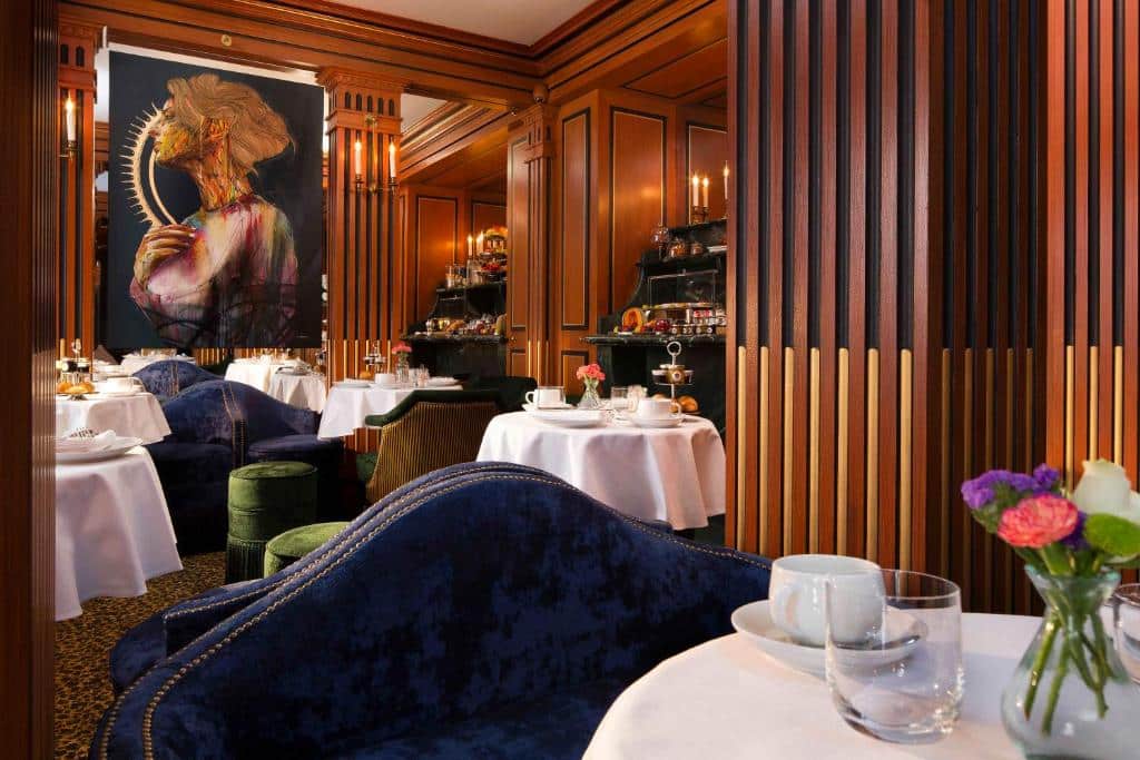 Restaurante elegante do La Chambre du Marais com cadeiras de veludo azul-escuro, toalhas brancas e painéis de madeira.