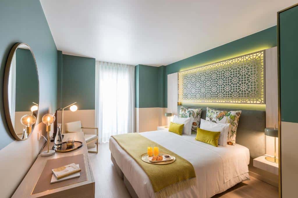 Quarto moderno no Hotel Estrela de Fátima com cama de casal, apontamentos a verde, cabeceira decorativa, secretária e tabuleiro de pequeno-almoço sobre a cama.