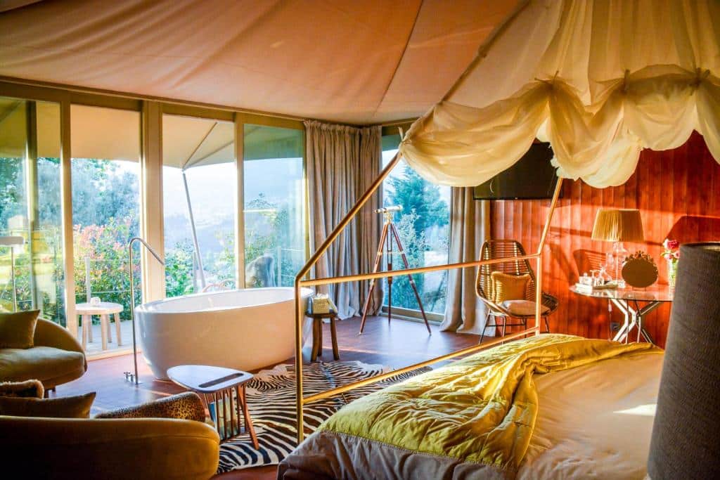 Quarto do Carmo’s Boutique Hotel, com cama de casal e banheira de hidromassagem em frente.