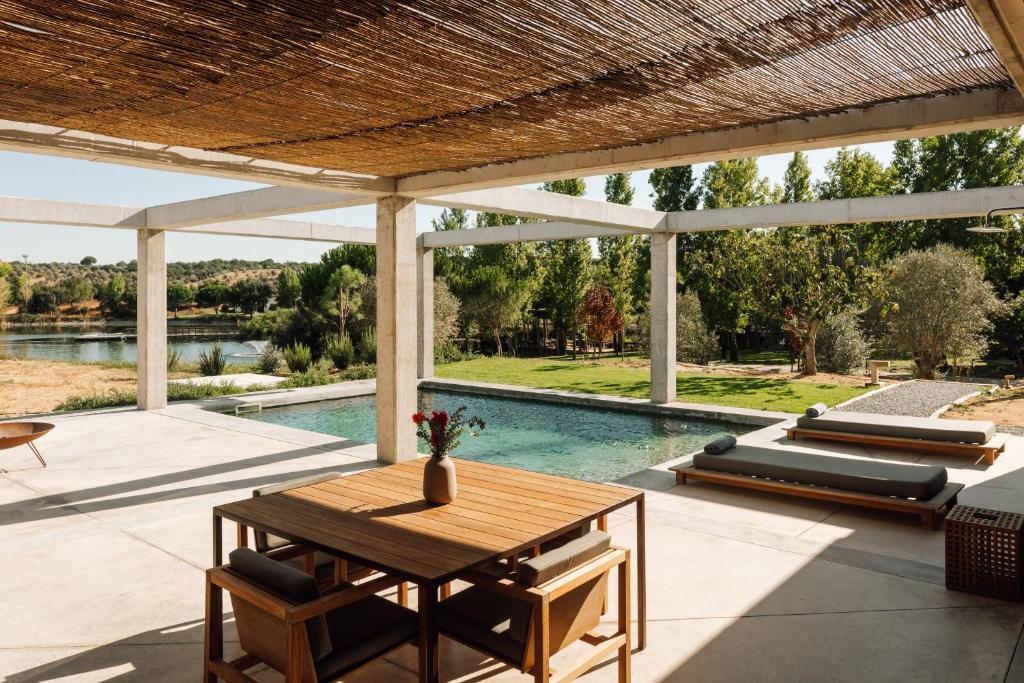 Varanda com mesa de madeira, piscina e vista para lago no L'AND Vineyards - Relais & Châteaux, em Montemor-o-Novo