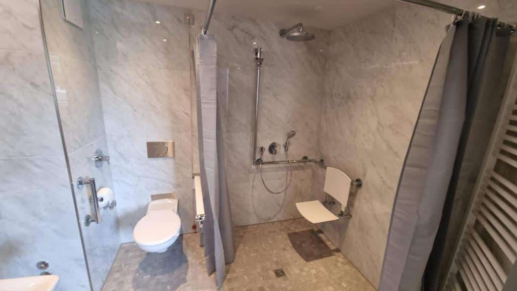 Casa de banho com acessibilidade do Fourty Three Luxury Serviced Apartments, com duche e sanita com barras de apoio.