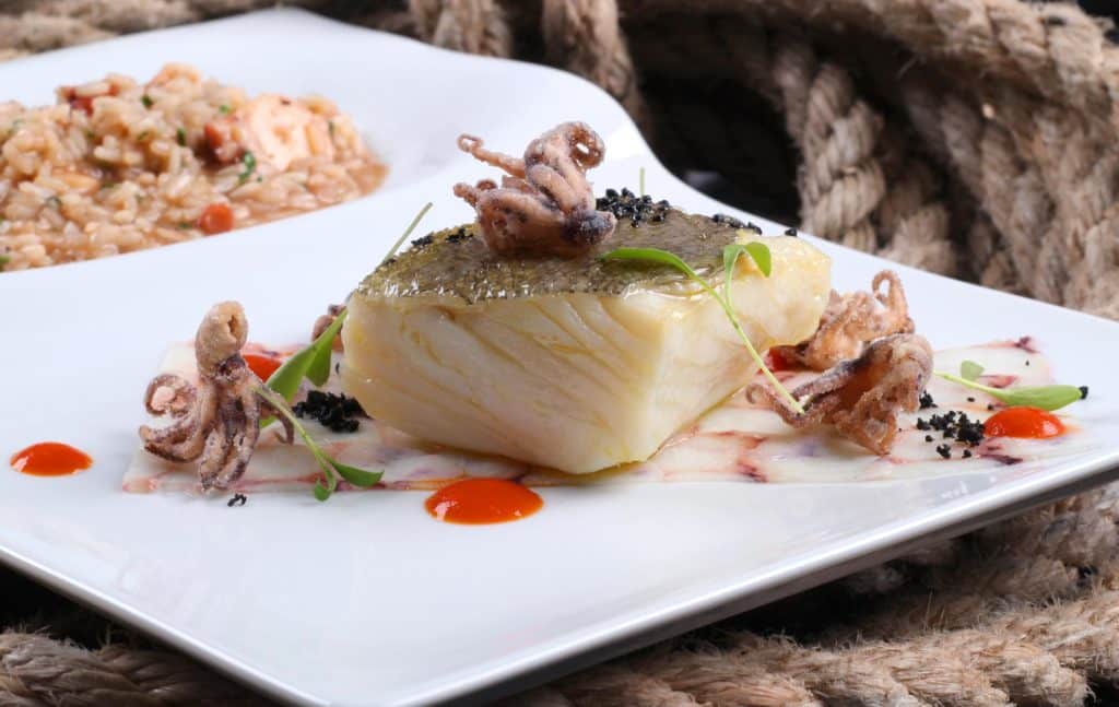Prato de filete de peixe com mini polvos e arroz, servido no restaurante SalPoente.