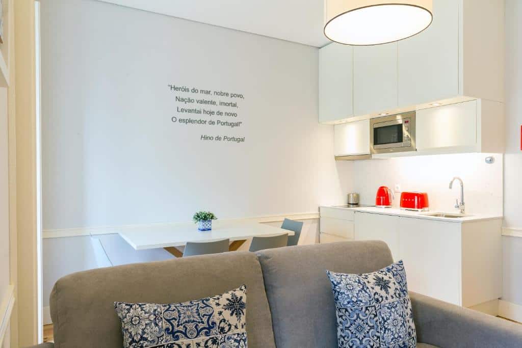 Cozinha do Villa Baixa - Lisbon Luxury Apartments com armários, micro-ondas, lava-loiça, chaleira e torradeira, além de uma pequena mesa com quatro cadeiras e uma janela do lado esquerdo
