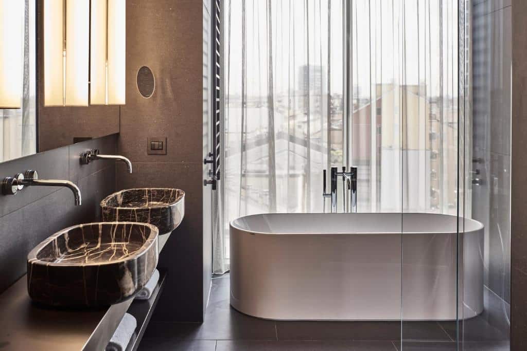 Casa de banho com banheira e vista sobre a cidade, com dois lavatórios, no Hotel VIU Milan