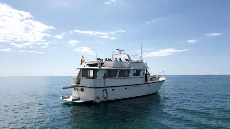 Iate de luxo branco e cinzento a navegar no mar azul sob um céu nublado, o Hotel Yacht Our Alissal.