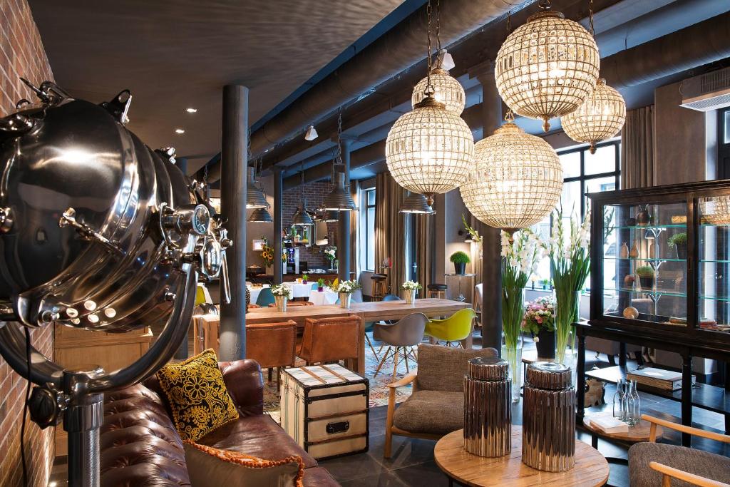 Sala de estar moderna do Hôtel Fabric com sofás de pele, candeeiros esféricos e grandes janelas com luz natural.