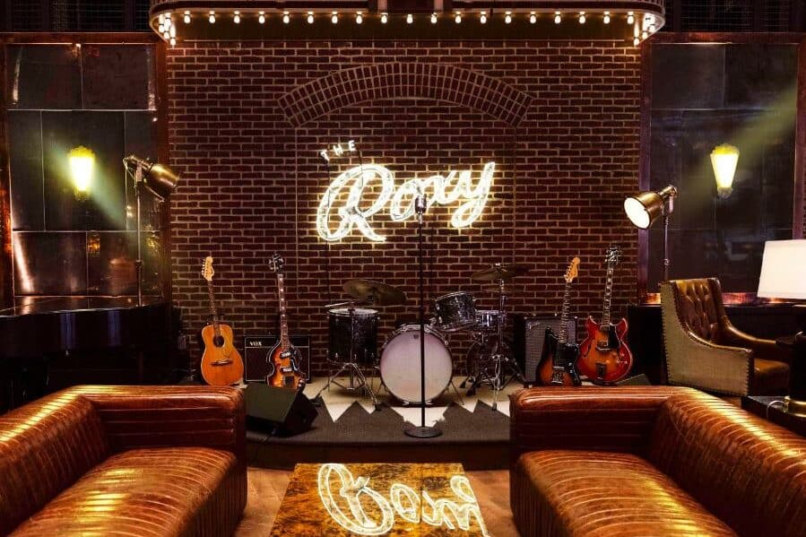 No palco do Roxy Hotel há uma bateria ao centro, rodeada de guitarras. Em frente, dois sofás de cabedal castanho de cada lado de uma mesa de centro. Na parede do fundo, um letreiro iluminado com o nome Roxy.