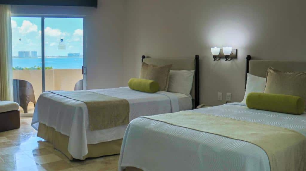 Quarto no Hotel Casa Maya com cama de solteiro e cama de casal e varanda, decorado em bege e verde