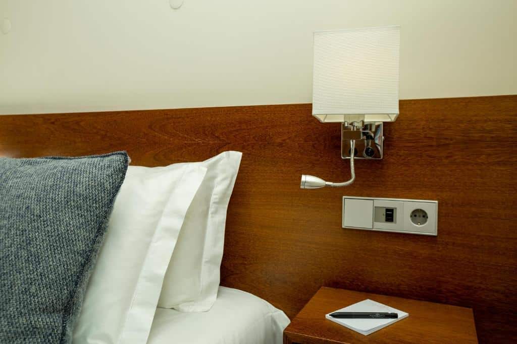 Quarto do Flores Lofts, com cama de casal à esquerda e, à direita, um candeeiro e uma cómoda.