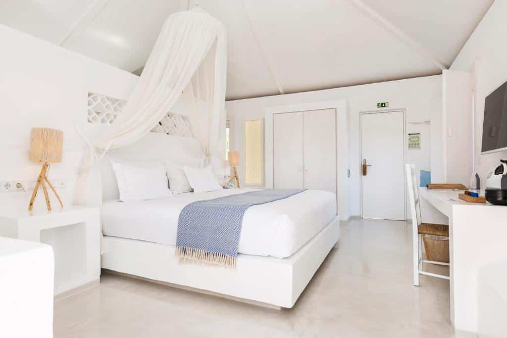 Quarto branco com cama de casal, colcha azul, secretária, cadeira e candeeiros, na Vila Monte Farm House em Moncarapacho.
