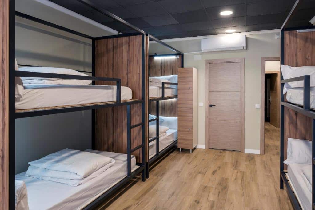Quarto de dormitório do SOM Hostel Valencia com beliches de madeira, portas de madeira, pavimento de madeira e ar condicionado.
