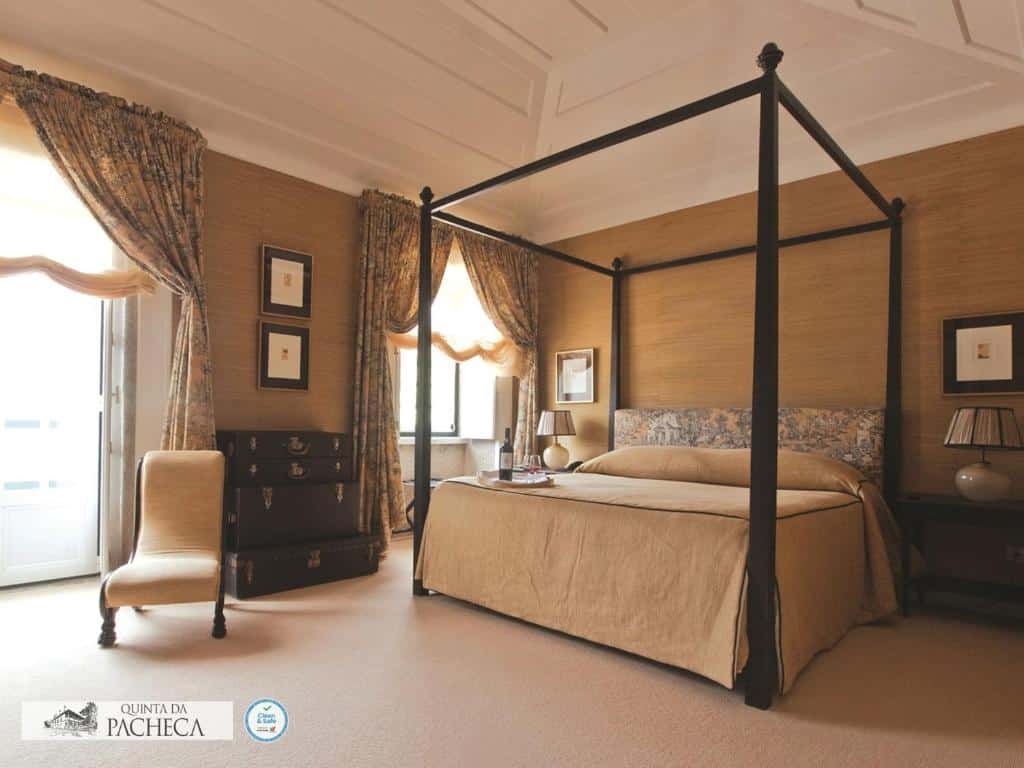 Quarto do The Wine House Hotel – Quinta da Pacheca, com cama de casal ao centro e mesas de cabeceira com candeeiros.