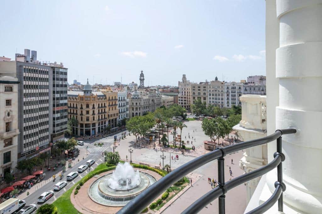 Praça no centro de Valência, com edifícios históricos, torre e fonte ao centro, junto ao Venecia Plaza Centro.