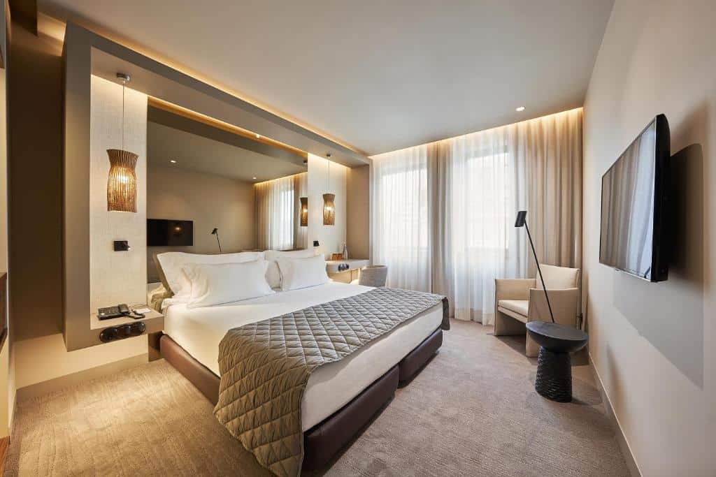 Quarto do PortoBay Teatro com cama de casal e televisão na parede em frente.