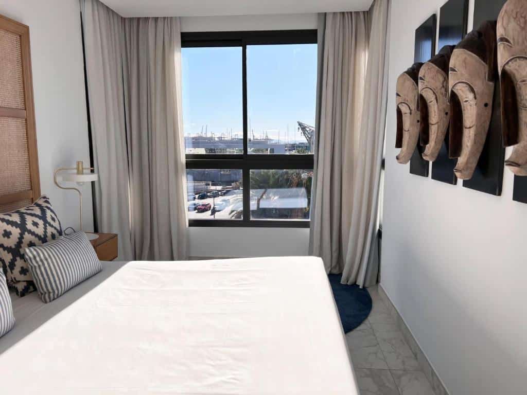 Quarto do Valencia Luxury com vista para o porto marítimo, decorado com móveis contemporâneos em tons neutros e um apontamento de tecido às riscas.