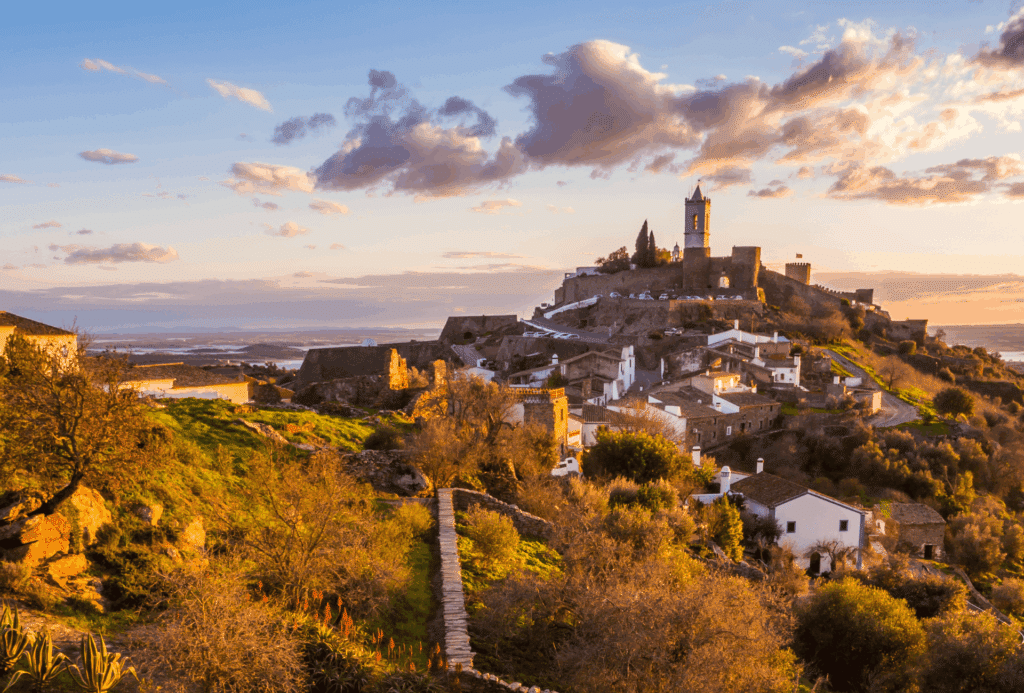Vila medieval com castelo e torre no topo de colina soalheira em Portugal. Ilustra este artigo sobre o que fazer em Évora.