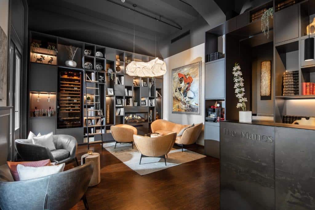 Lounge moderno do The Manes Boutique Hotel Prague, com cadeiras de couro, estantes, garrafeira, arte contemporânea e balcão de receção.