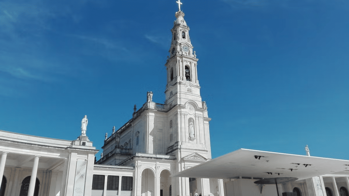 Igreja ao centro durante o dia, com céu azul.