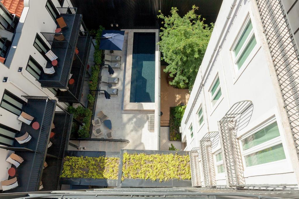 Terraço do Hotel Valverde Lisboa, com uma piscina, espreguiçadeiras e árvores no deck, vendo-se também as varandas de alguns quartos