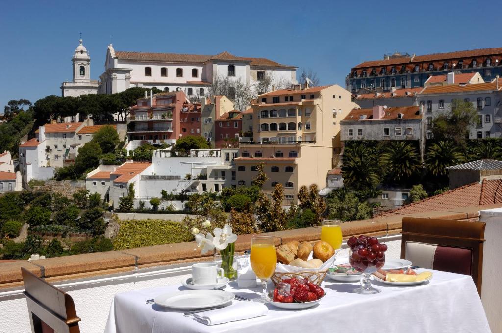 Varanda do Olissippo Castelo com vista para a torre do Castelo de São Jorge, com uma mesa posta para pequeno-almoço para duas pessoas.