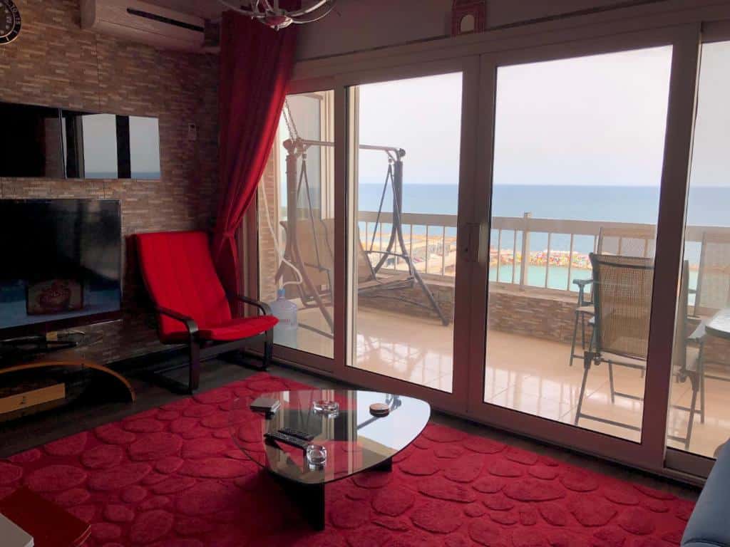 Vista do interior do apartamento Blue Bay Beach, em Alexandria, decorado em tons de vermelho, com vista do rio a partir da varanda