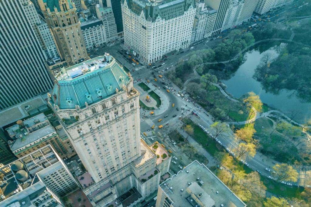 Vista aérea de edifícios altos junto ao Central Park, com árvores, estradas e táxis amarelos em Nova York.