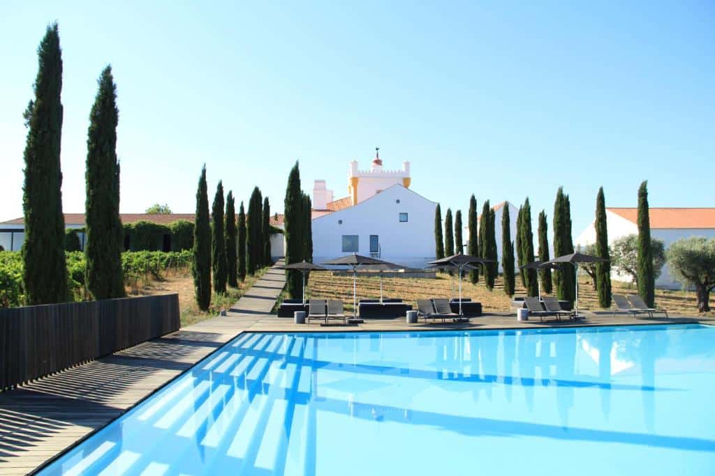 Piscina ao ar livre do Torre de Palma Wine Hotel com espreguiçadeiras e guarda-sóis.