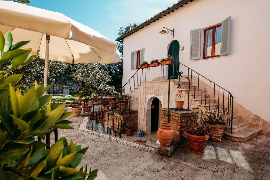 Casa de campo com fachada clara, jardim florido e chapéu de sol branco em zona exterior soalheira
