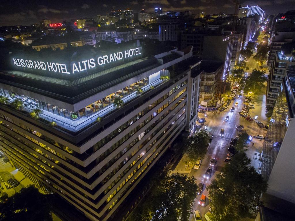 Vista aérea noturna do Altis Grand Hotel com as ruas da cidade e os semáforos ao fundo.