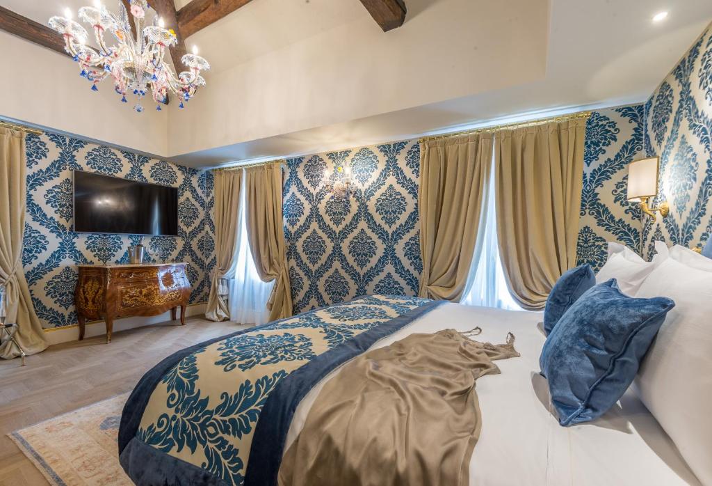 Quarto decorado em estilo barroco com paredes com padrão em tons de azul, cortinas douradas e candelabro de cristal no teto