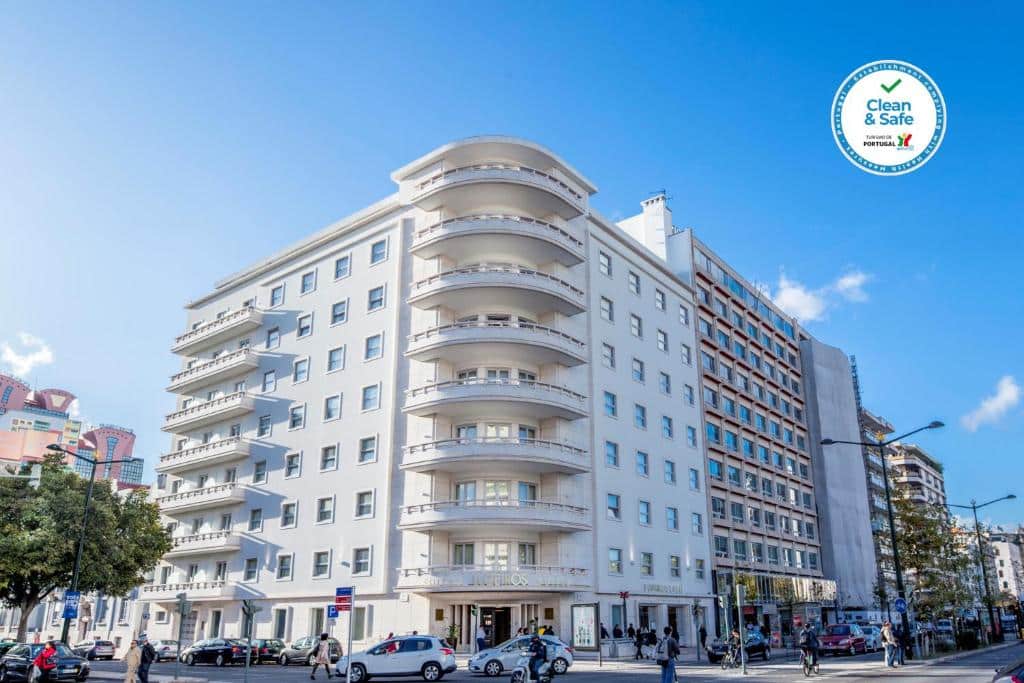 Edifício de época do Luzeiros Suites numa esquina, com oito andares e algumas varandas viradas para uma rua movimentada.