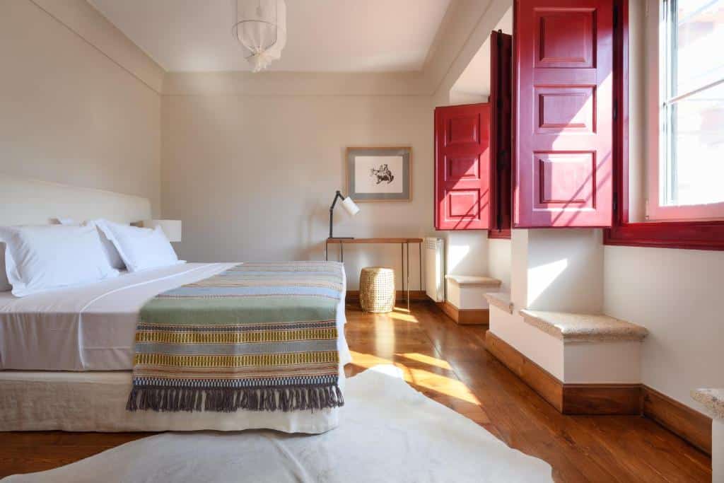 Quarto de casal com cama branca e colcha colorida na A Casa do Governador, em Évora