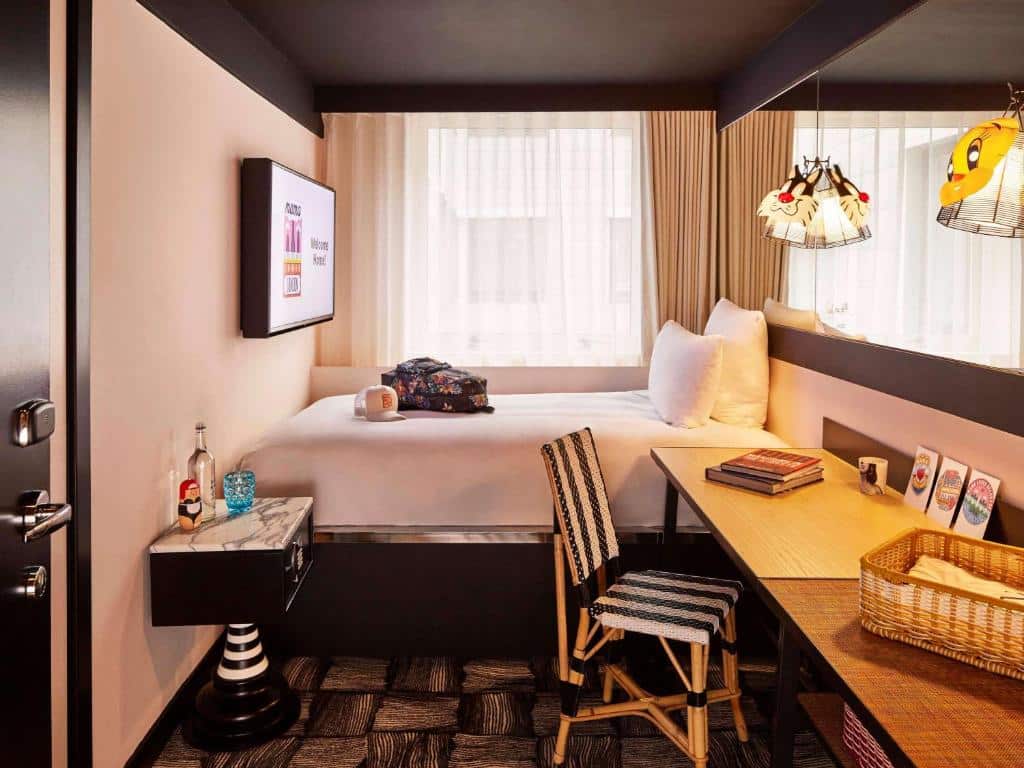Quarto do Mama Shelter London – Shoreditch com cama de casal, janela com cortinas, televisão, espelho e secretária com cadeira