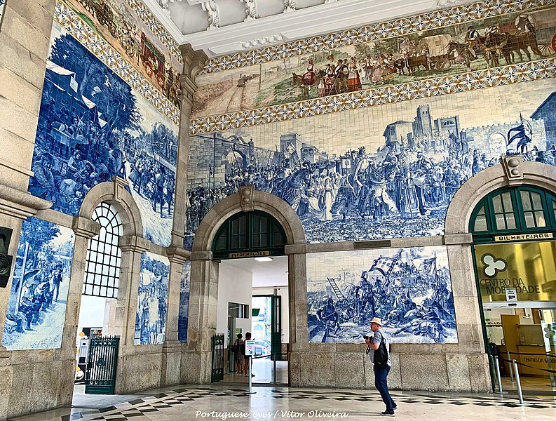 Interior da Estação Ferroviária de São Bento, com paredes revestidas de azulejos que retratam a história do país.
