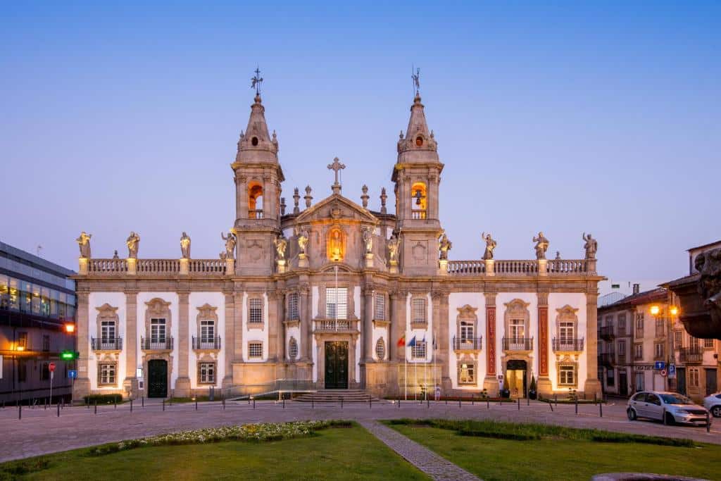 Edifício histórico do Vila Galé Collection Braga, com torres sineiras gémeas e estátuas, iluminado ao entardecer.
