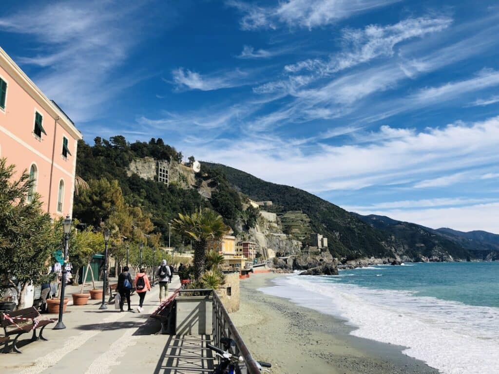 Praia e casas junto ao mar em Monterosso al Mare, com céu azul e nuvens