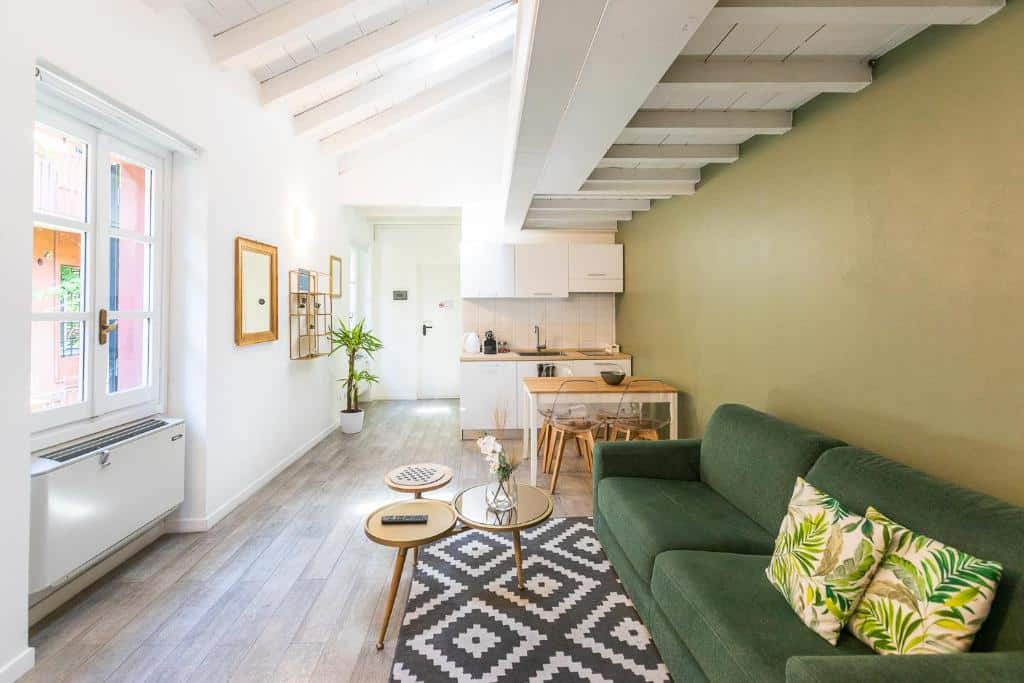 Sala de estar com kitchenette do Alzaia Naviglio Grande com sofá com almofadas, janela, mini-cozinha equipada, mesa de quatro lugares e mesa de centro