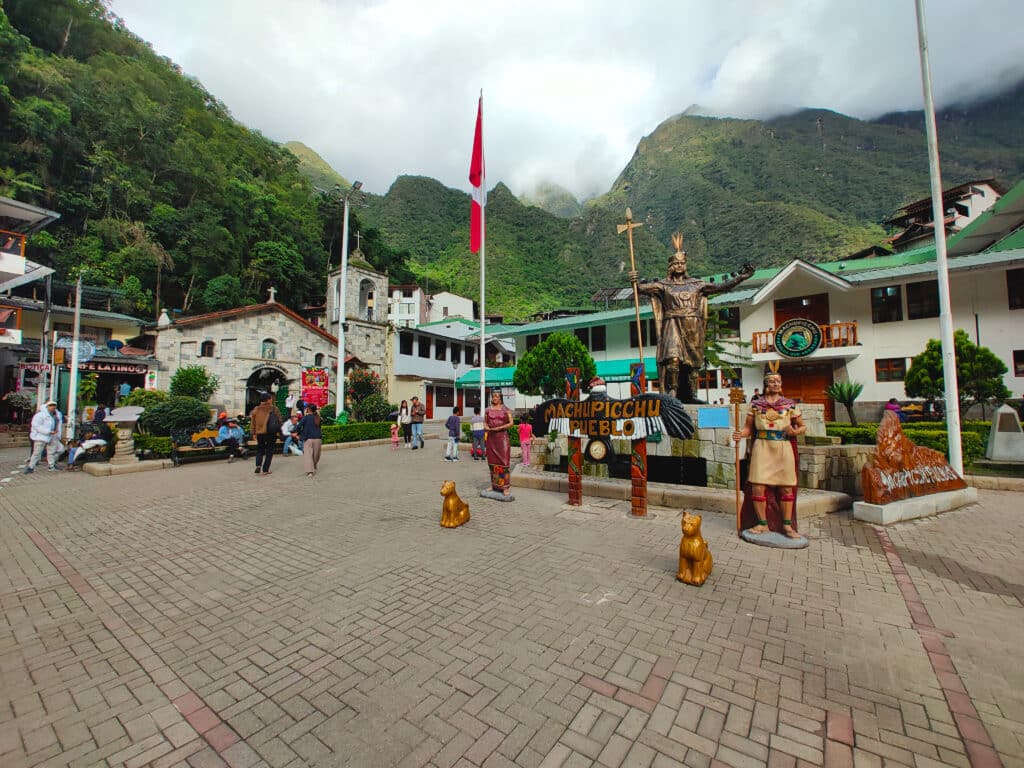 Praça Manco Capac em Machupicchu Pueblo, com a igreja ao fundo e as montanhas em redor cobertas de nuvens