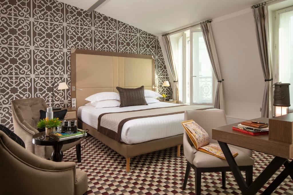 Quarto do Philéas Lazare & Spa com cama de casal, paredes e pavimento estampados, secretária e uma grande janela com cortinas.