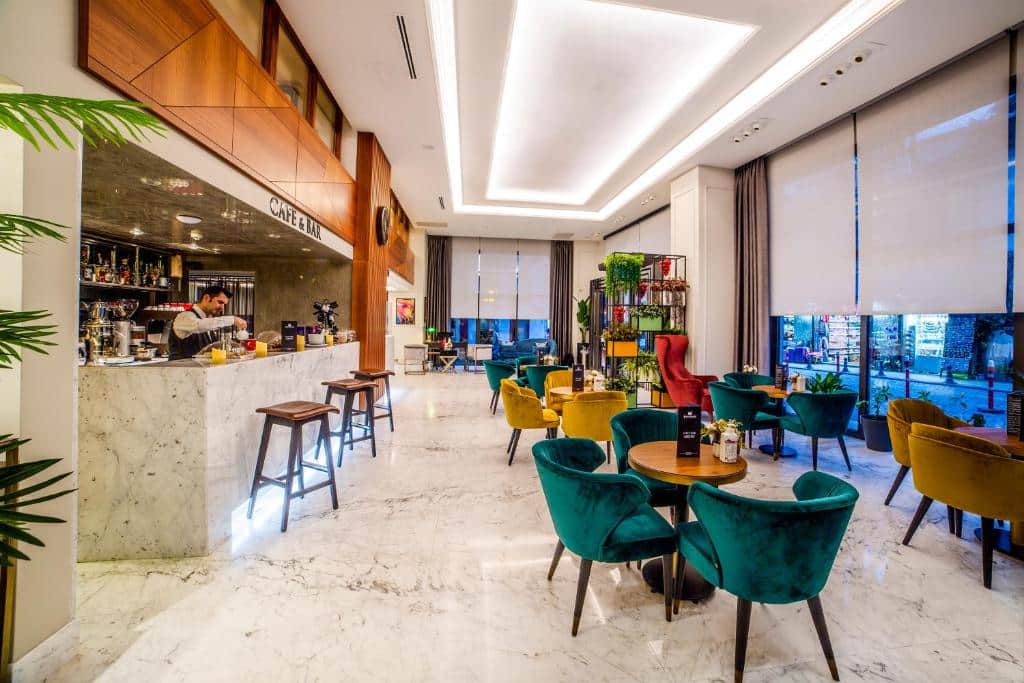 Lounge moderno do Erboy Hotel Istanbul Sirkeci com pavimento de mármore, cadeiras coloridas, um balcão de bar e janelas grandes com estores.