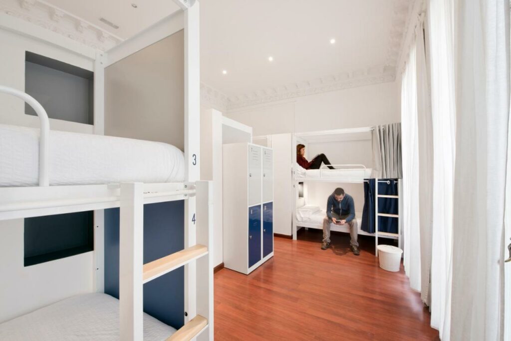 Quarto partilhado do The Central House Barcelona Gracia, com dois beliches numerados, cortinas e cacifos individuais.