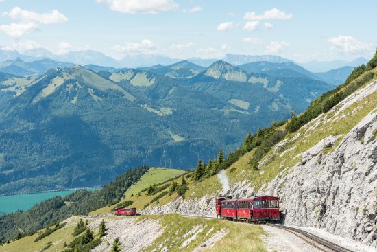 O comboio Schafbergbahn a subir a montanha com vista sobre os Alpes.