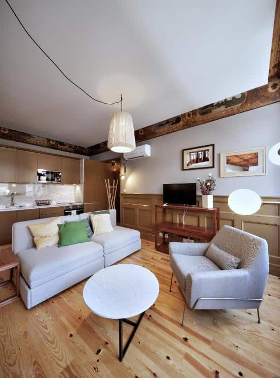Sala do Aparthotel Oporto Batalha, com poltrona à direita, um sofá à esquerda e uma mesa redonda ao centro.