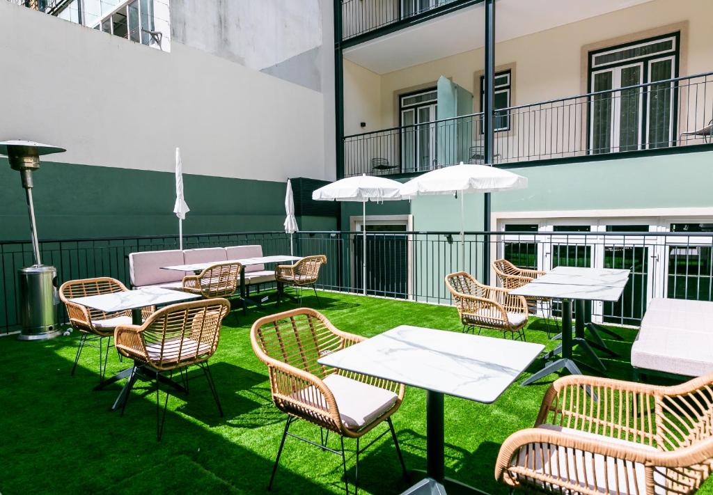 Espaço exterior nas traseiras do LX SoHo Boutique Hotel com mesas quadradas, cadeiras e alguns chapéus de sol brancos.