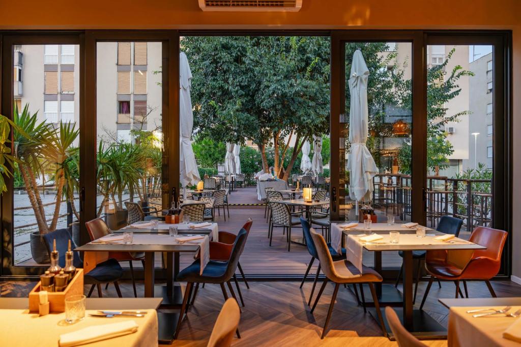 Restaurante com mesas ao ar livre e vista para área verde com árvores e chapéus de sol, no Hotel A’mare
