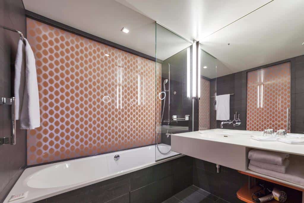 Casa de banho moderna do Radisson Blu Hotel, com banheira e azulejos cinzentos.