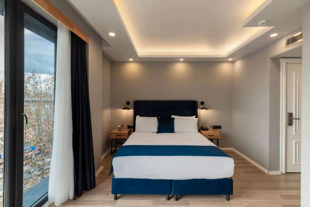 Um quarto moderno do Union Hotel Karaköy com uma cama de casal, duas mesas de cabeceira, pavimento de madeira e uma janela com cortinas.