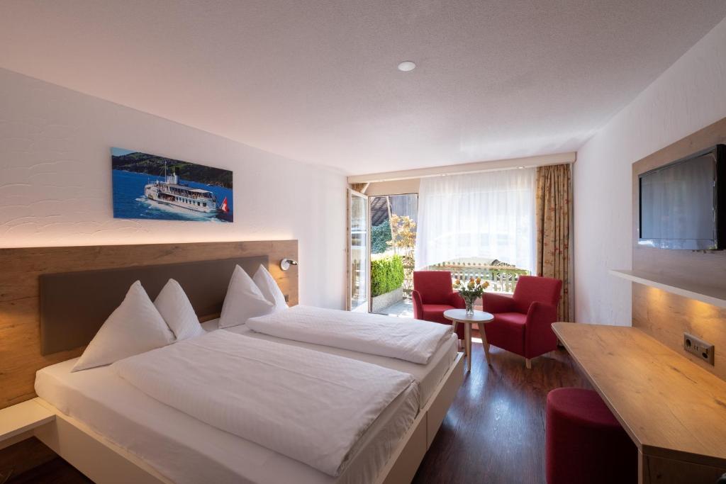 Quarto do Hotel Chalet Swiss com cama de casal, poltronas e porta para a varanda.
