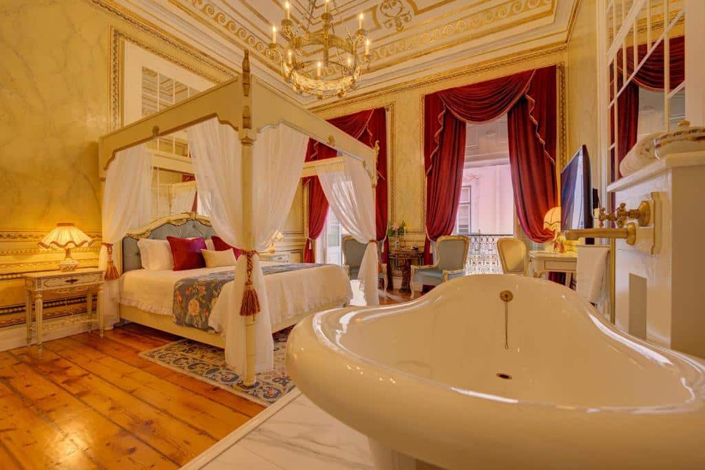 Quarto luxuoso do Palácio das Especiarias, com duas varandas de cortinas vermelhas, uma cama de casal com dossel em tecido branco, um lustre dourado e uma banheira de hidromassagem